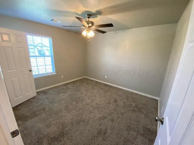 an empty room with windows and fan