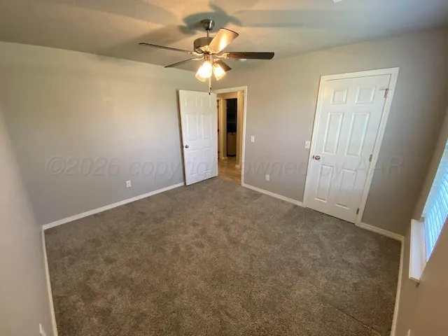an empty room with a ceiling fan and a window
