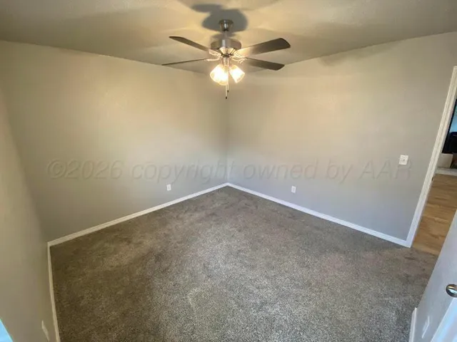 an empty room with a chandelier fan and windows