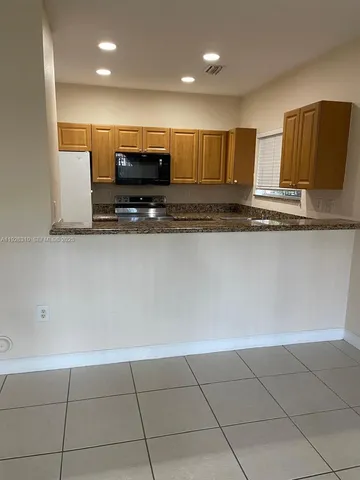 a view of kitchen with stainless steel appliances wooden floor and large counter top