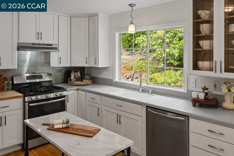 a kitchen with stainless steel appliances granite countertop a stove a sink and a white cabinets