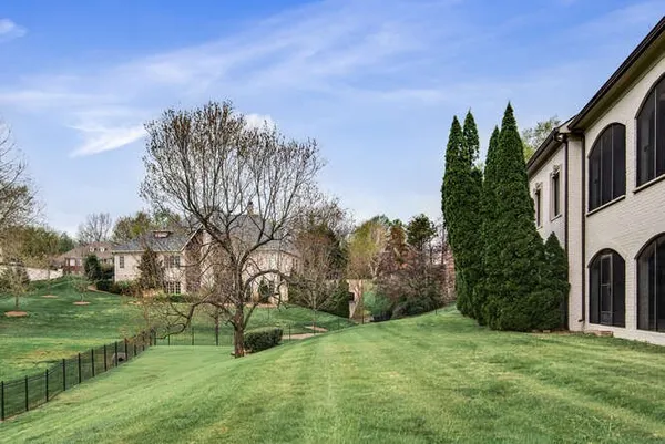 a view of a house with a small yard and a large tree