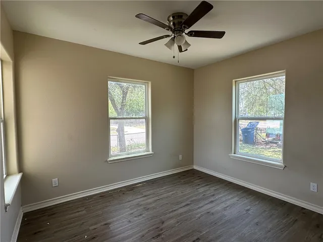 a view of an empty room with a window and wooden floor