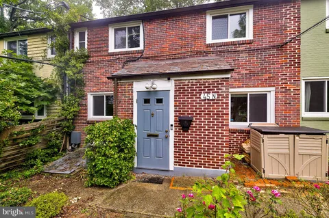 a view of a brick house with large windows and flower plants