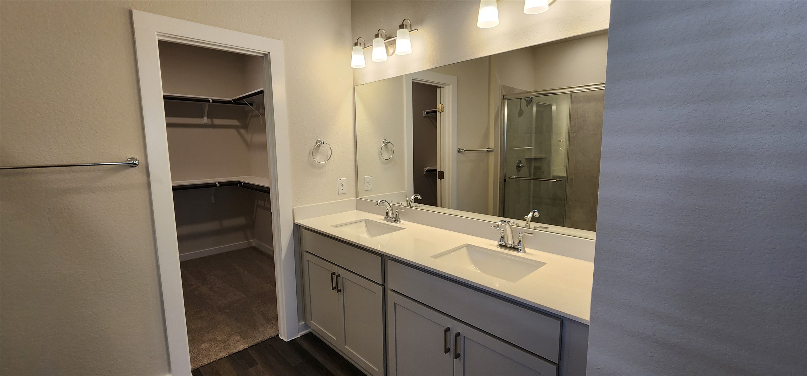 2240 Delano Drive Leander, TX 78641 - Photo 12 of 32 Bathroom featuring double vanity, a stall shower, a walk in closet, dark wood-style flooring, and a textured wall