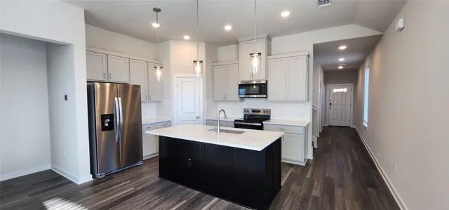 a kitchen with a refrigerator a sink and wooden floor