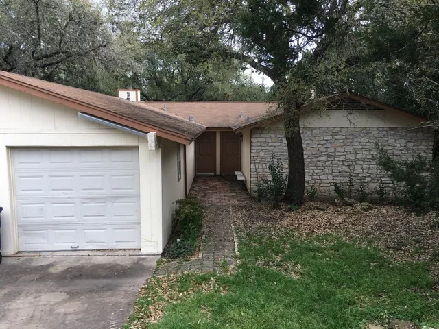 a backyard of a house with plants and large tree
