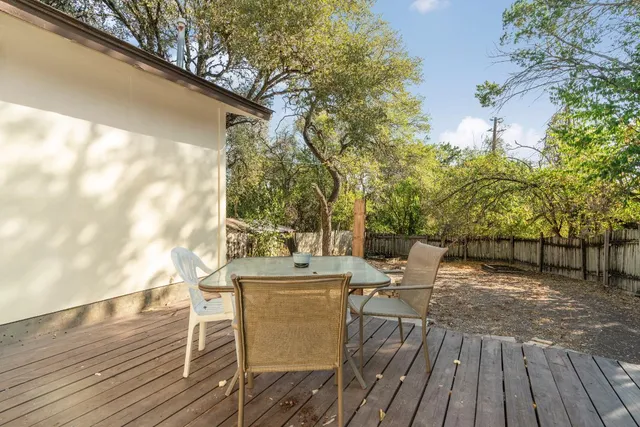 a view of a patio with table and chairs and couches with wooden floor and fence