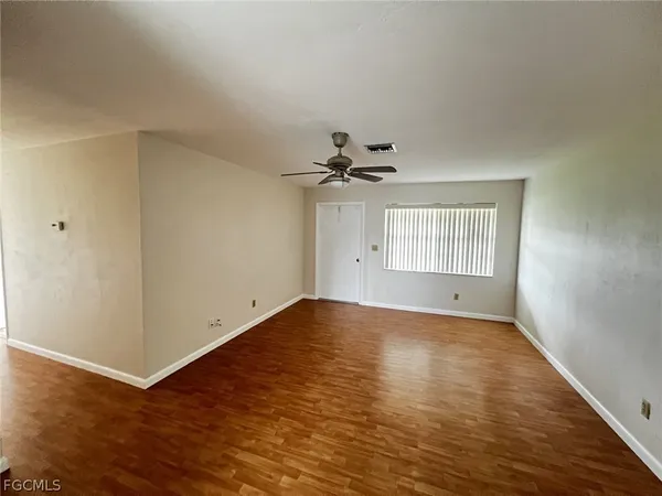 a view of an empty room with wooden floor and a window