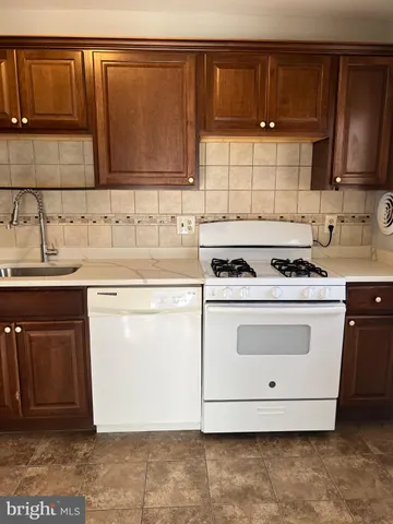 a kitchen with granite countertop a sink a stove and cabinets