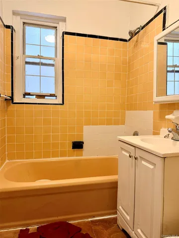 a bathroom with a granite countertop sink a mirror and a bathtub