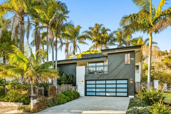 a front view of a house with a yard and potted plants