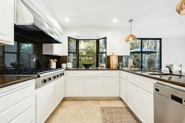 a kitchen with stainless steel appliances kitchen island granite countertop a stove and a sink