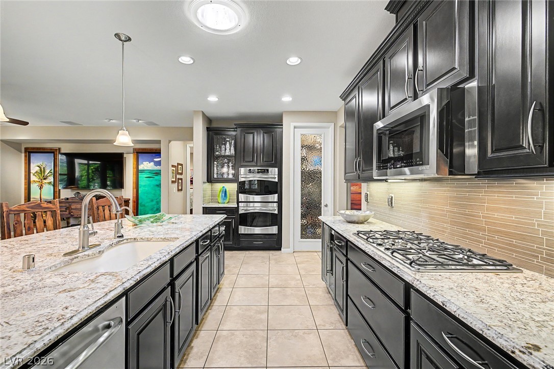 7415 Campbell Ranch Avenue Las Vegas, NV 89179 - Photo 19 of 52 Granite counters and dark wood cabinetry define this well-appointed kitchen with abundant storage and premium appliances.