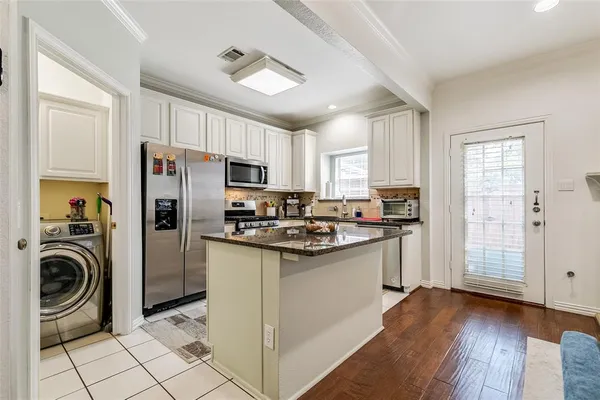 a kitchen with kitchen island a sink a stove a refrigerator cabinets and a window