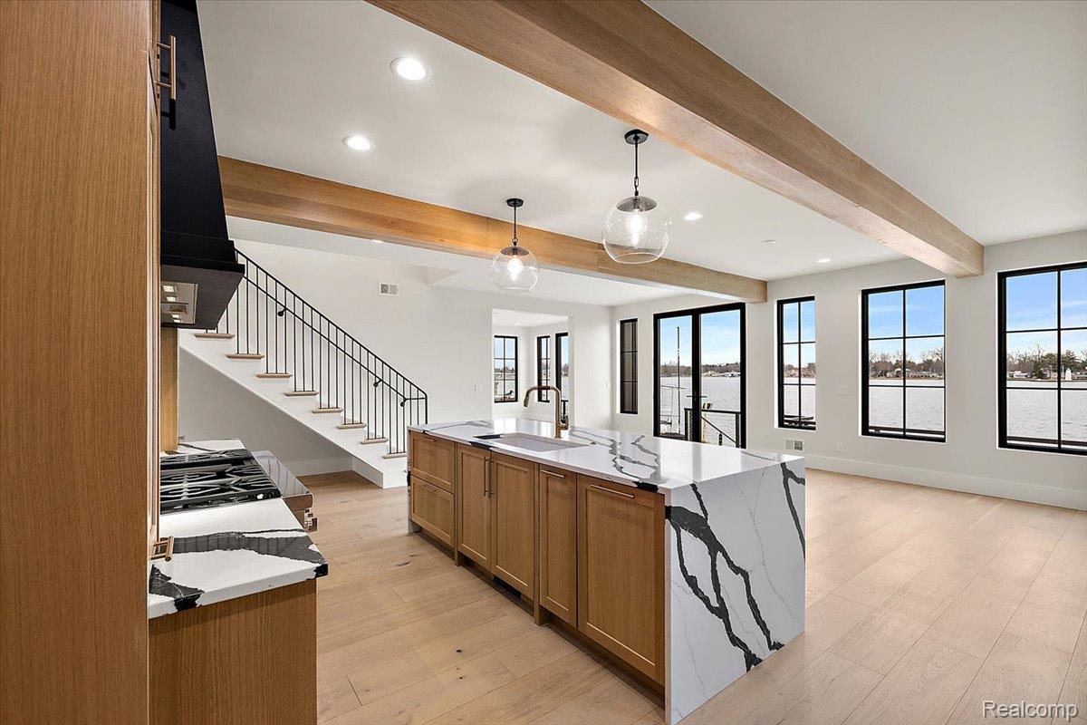 13459 Haddon Street Fenton, MI 48430 - Photo 78 of 84 Kitchen featuring wood finish cabinetry, open floor plan, hanging light fixtures, a kitchen island with sink, and light stone counters
