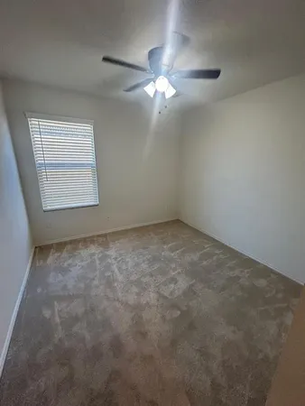 an empty room with a chandelier fan and windows
