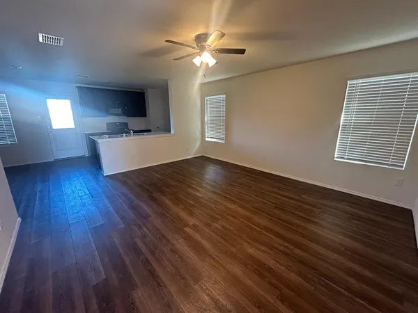 a view of kitchen and empty room with wooden floor
