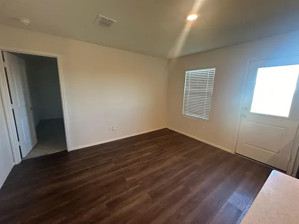 an empty room with a chandelier fan and windows