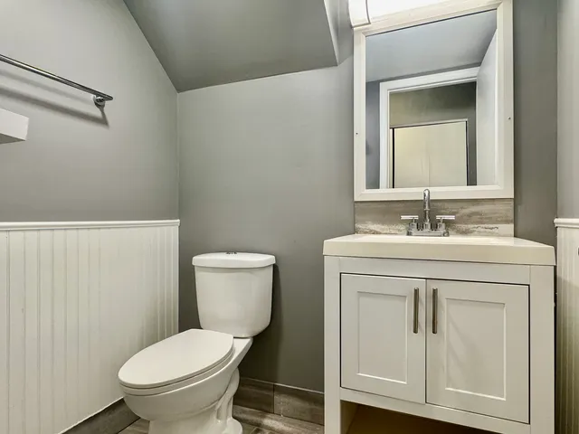 a bathroom with a toilet sink vanity and mirror