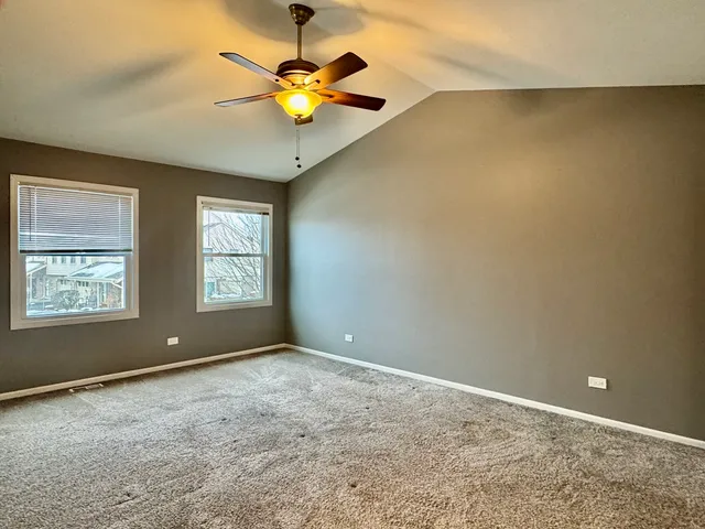 an empty room with windows and chandelier fan