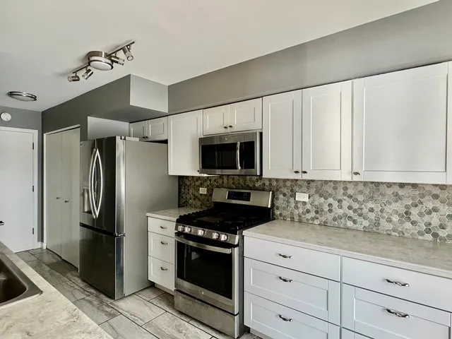 a kitchen with white cabinets and stainless steel appliances