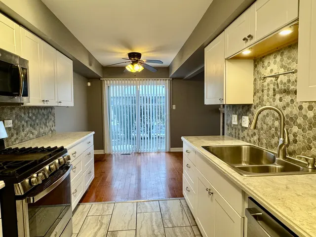 a kitchen with granite countertop a sink a counter space appliances and cabinets