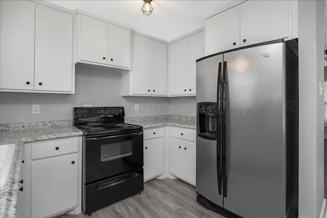 a kitchen with stainless steel appliances granite countertop a refrigerator stove and white cabinets