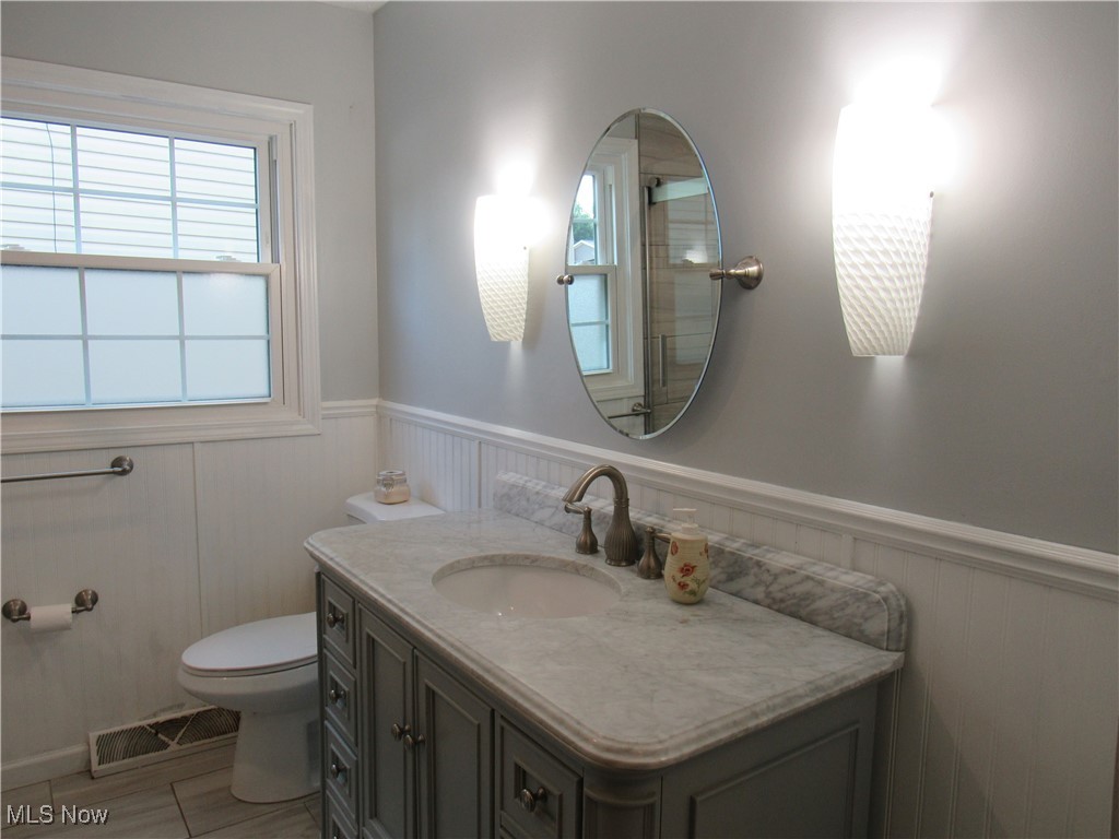 1120 Vincent Road Southeast North Canton, OH 44720 - Photo 29 of 50 Main Bathroom featuring vanity, toilet, chair rail, wainscot, and tile patterned flooring