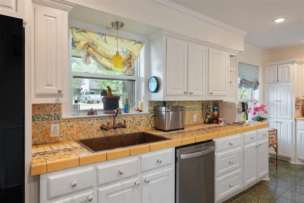 a kitchen with white cabinets and window