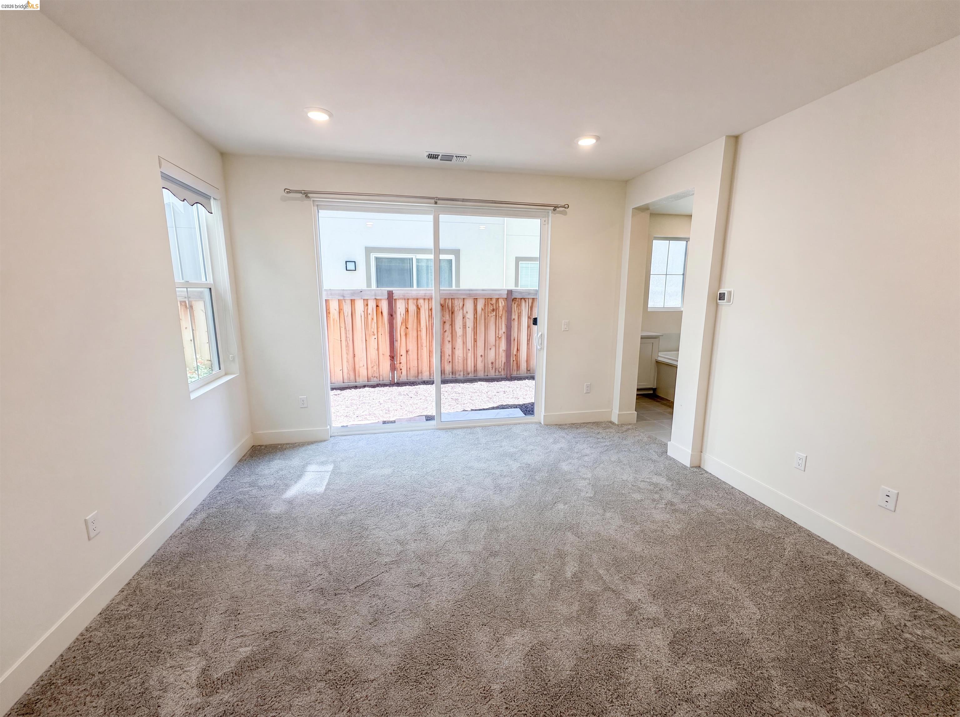 9034 Rudder Way Newark, CA 94560 - Photo 7 of 38 Spacious room featuring neutral carpeting, recessed lighting, and a large sliding glass door opening to a private outdoor area