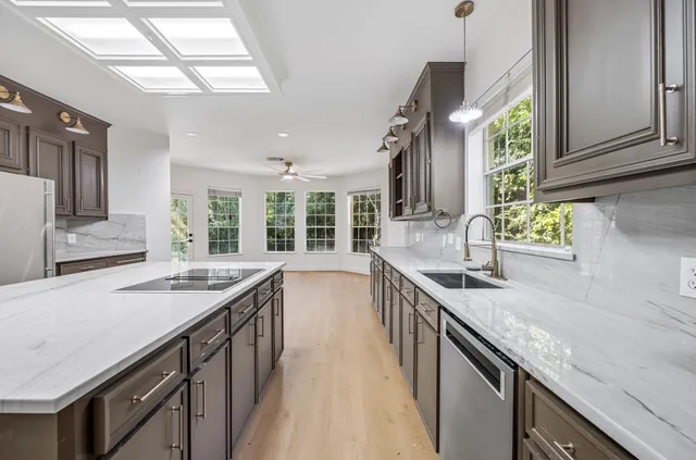 a kitchen with granite countertop kitchen island a sink appliances cabinets and a counter top space