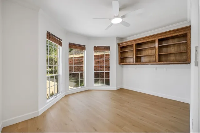 a view of an empty room with a window and wooden floor