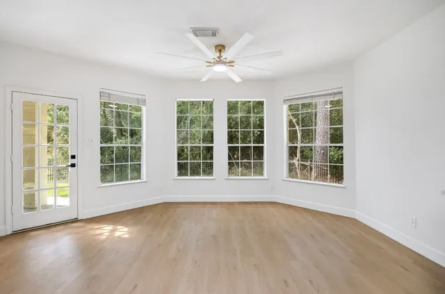 a view of an empty room with wooden floor and a window