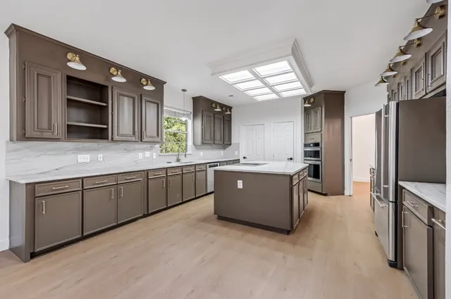 a large kitchen with stainless steel appliances kitchen island granite countertop a large counter top a stove a sink dishwasher and a refrigerator