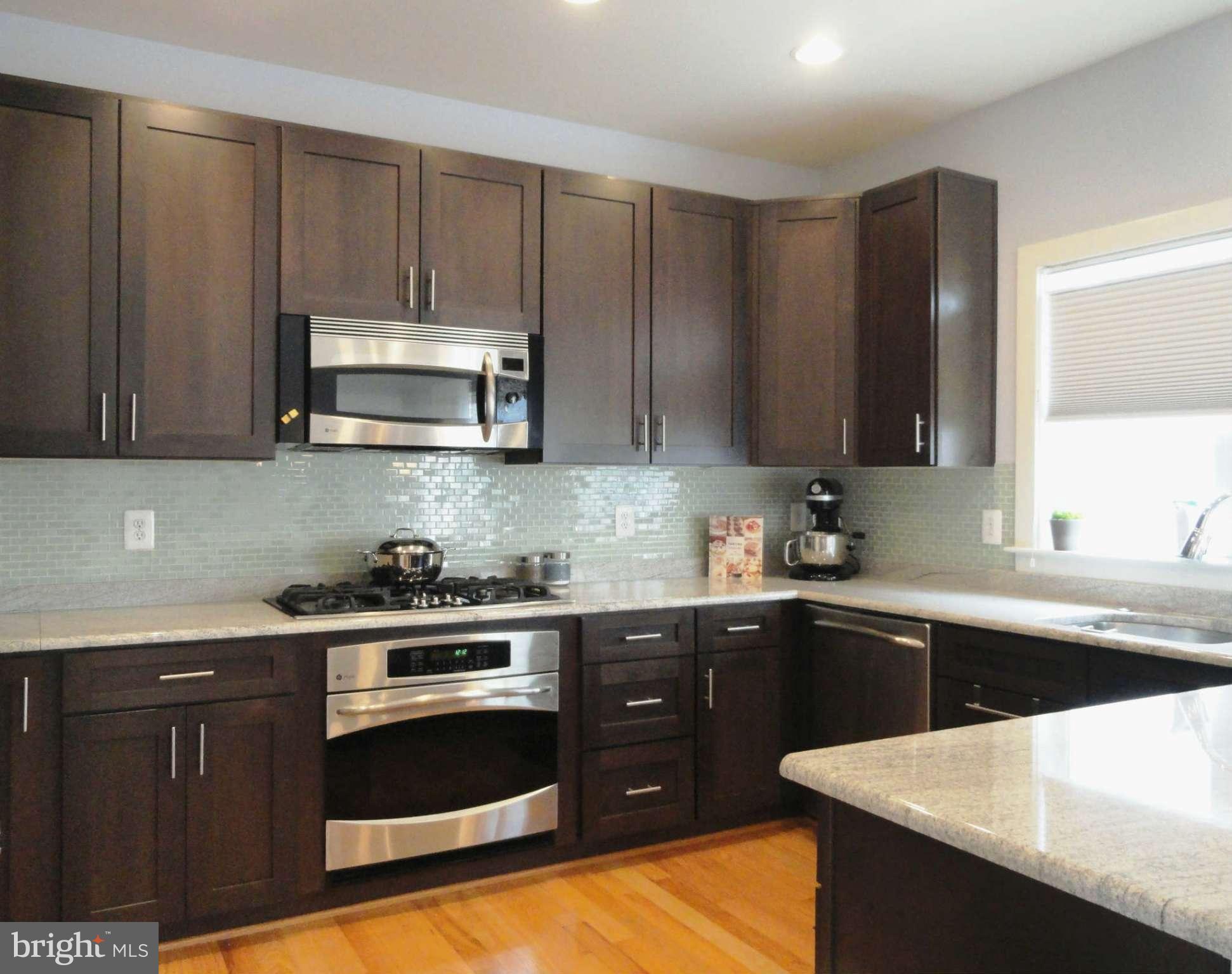 4159 Legato Road Fairfax, VA 22033 - Photo 8 of 25 a kitchen with stainless steel appliances a sink a stove a microwave a sink and cabinets