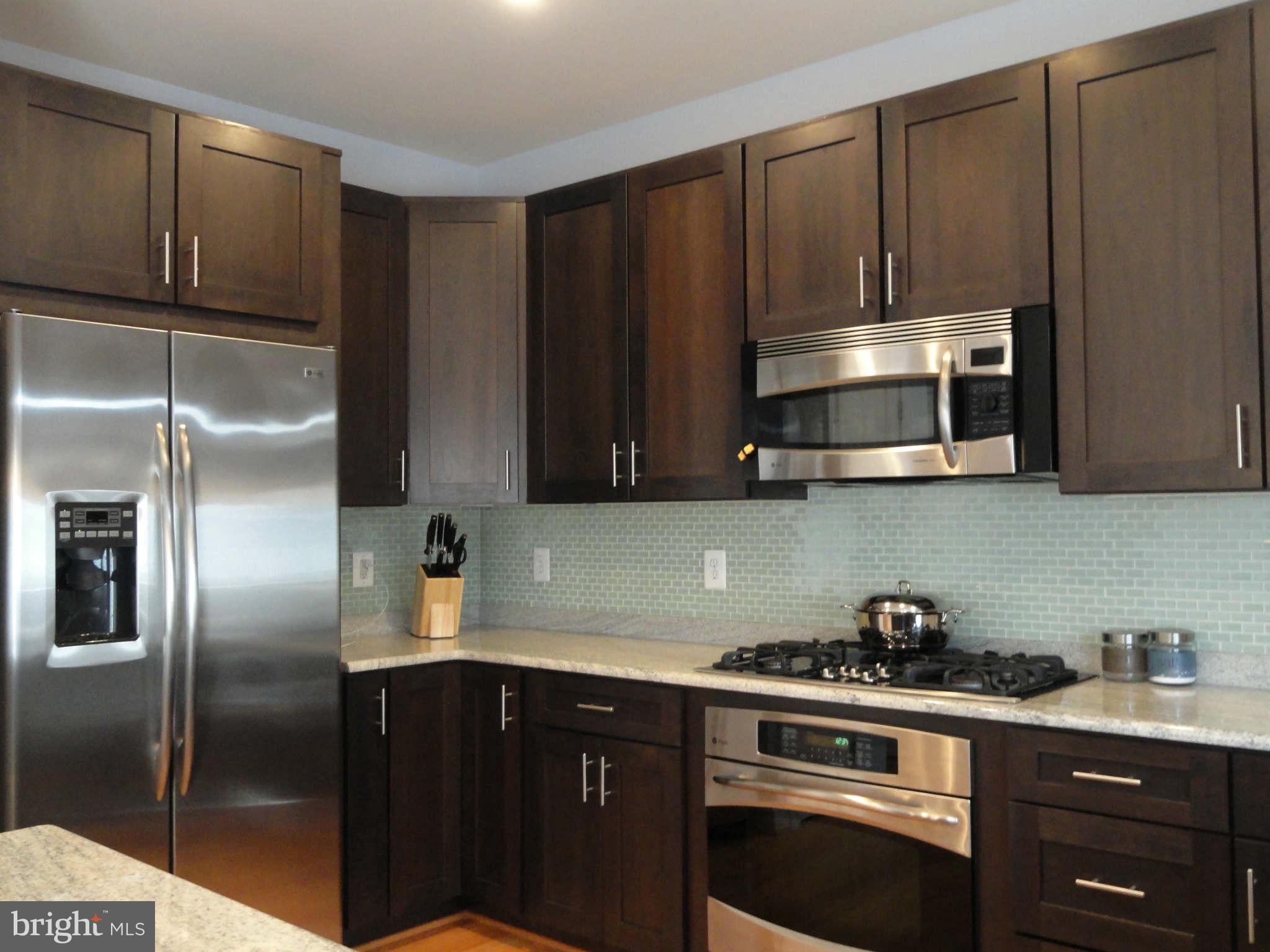4159 Legato Road Fairfax, VA 22033 - Photo 9 of 25 a kitchen with granite countertop a refrigerator stove and microwave