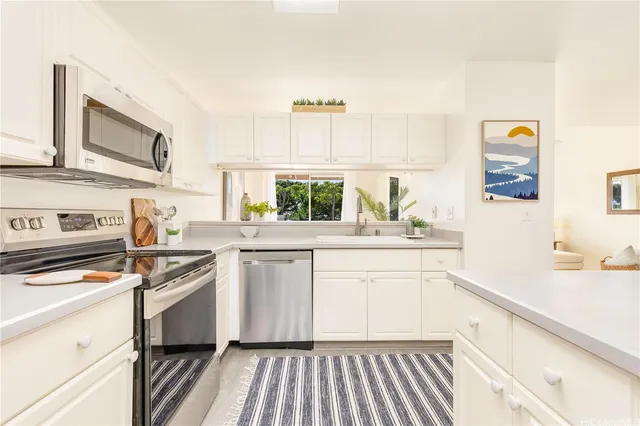 a kitchen with granite countertop a sink cabinets stainless steel appliances and a window