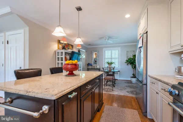 a kitchen with stainless steel appliances kitchen island granite countertop a table chairs and a refrigerator
