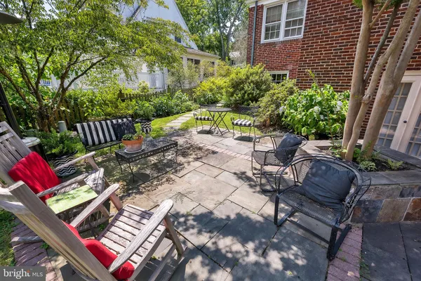 a view of a patio with table and chairs potted plants and large tree