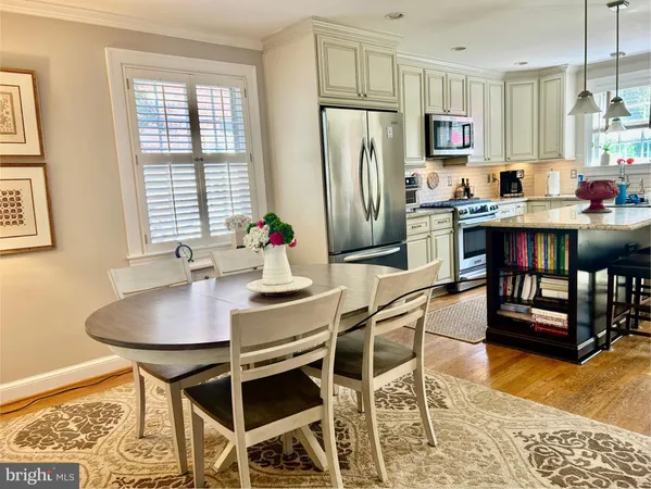 a kitchen with stainless steel appliances kitchen island granite countertop a dining table chairs and a refrigerator