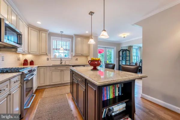 a kitchen with stainless steel appliances granite countertop a stove a sink dishwasher and a refrigerator with wooden floor