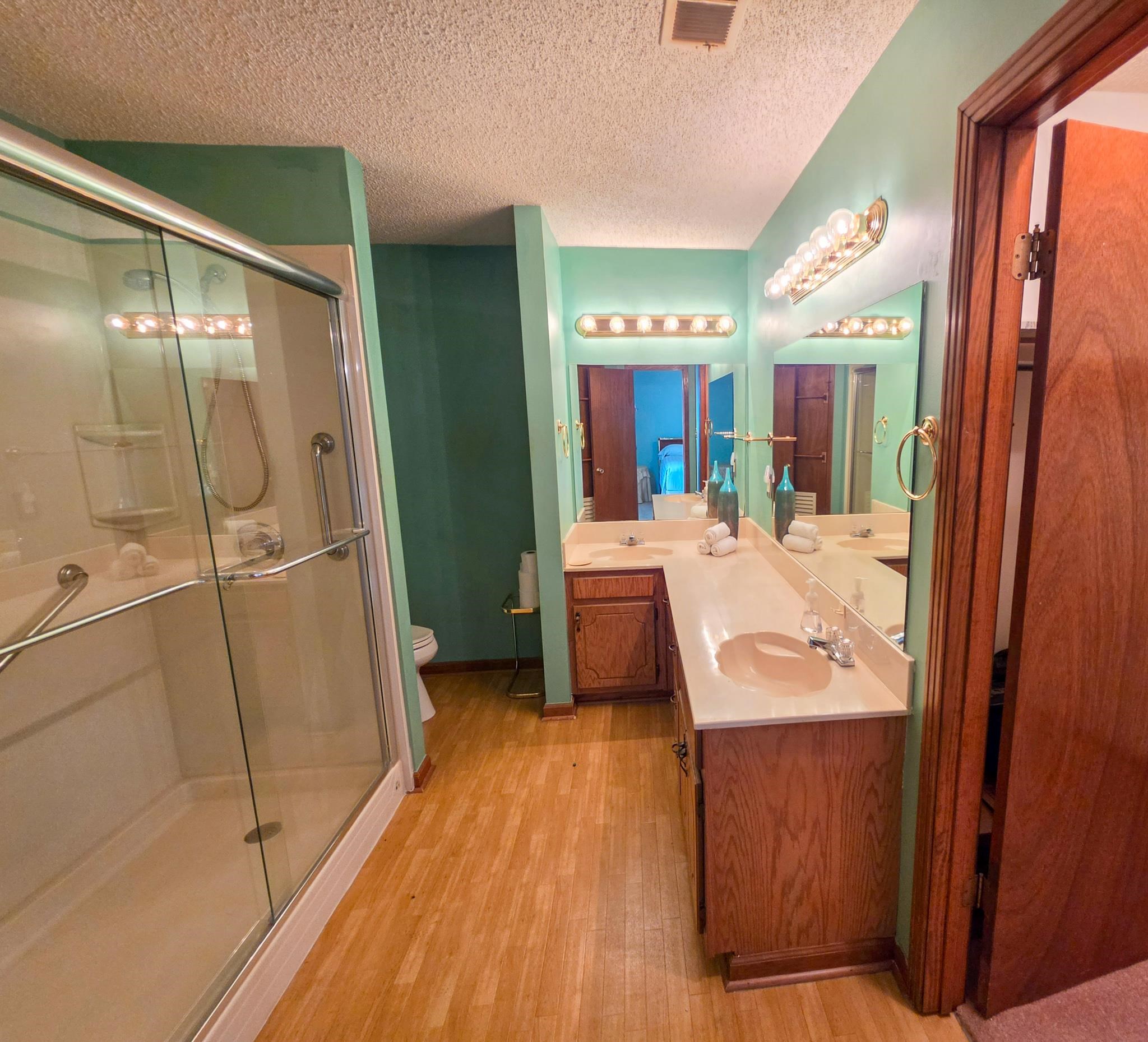 966 Beaver Road Munford, TN 38058 - Photo 10 of 32 Bathroom featuring a glass-enclosed shower, dual vanity with integrated sinks, wood-finish flooring, and a vanity-width mirror with overhead lighting