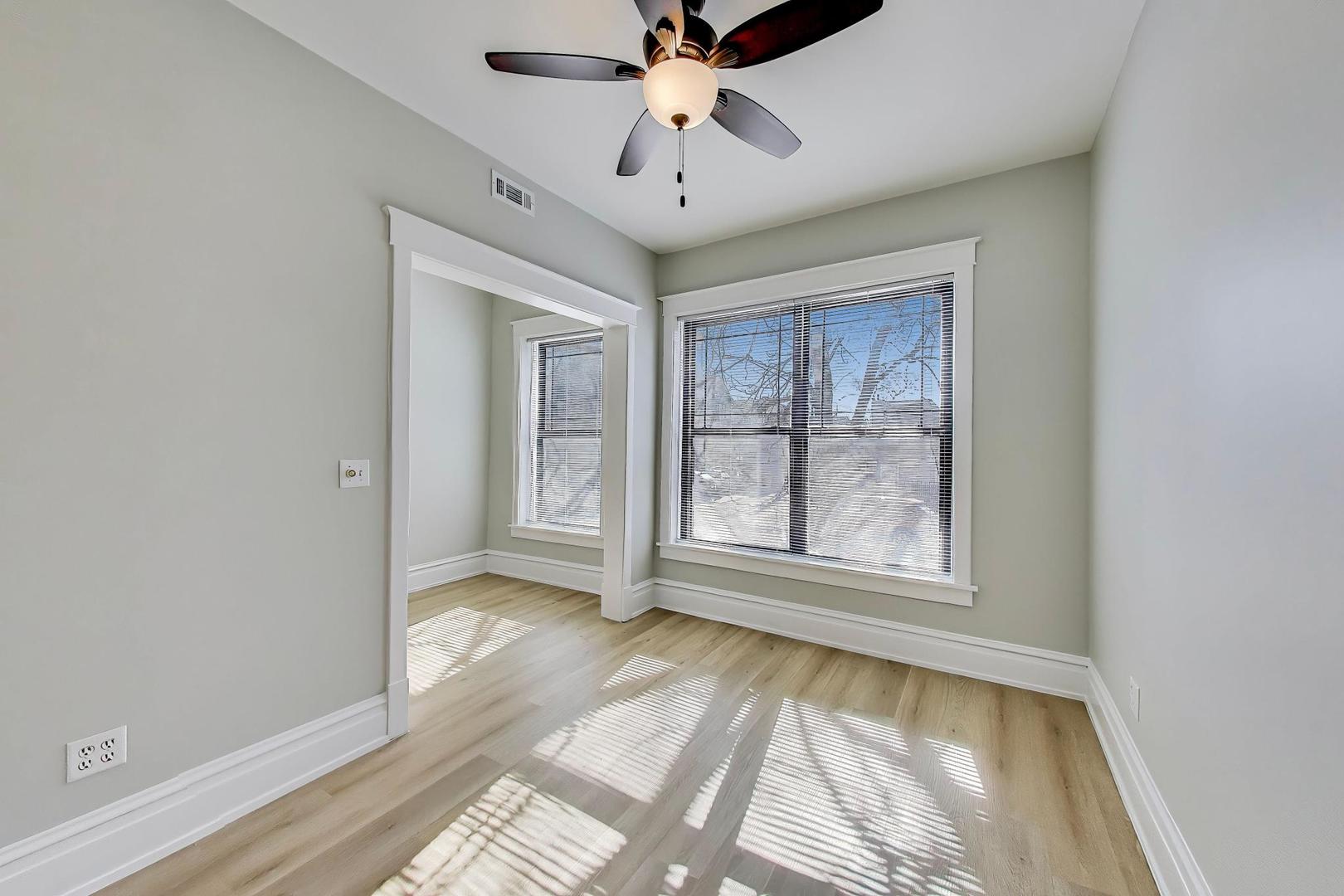 2114 West Byron Street, Unit 1 Chicago, IL 60618 - Photo 10 of 23 an empty room with chandelier fan and windows
