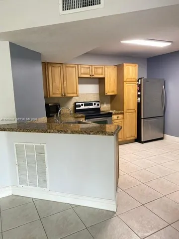 a kitchen with stainless steel appliances granite countertop a stove a sink and a refrigerator