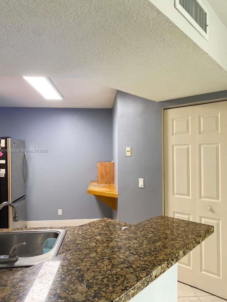 8901 Wiles Road, Unit 103 Coral Springs, FL 33067 - Photo 9 of 14 a bathroom with a granite countertop sink and a mirror