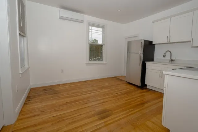 a view of an empty room with a kitchen and a window