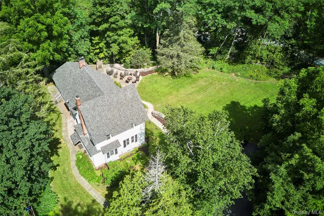 an aerial view of a house with yard and trees all around