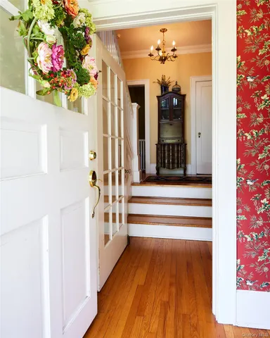 a view of a hallway with wooden floor and a chandelier