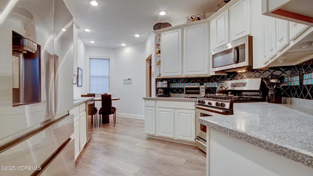 a kitchen with stainless steel appliances granite countertop a stove top oven a sink a dining table and chairs with wooden floor